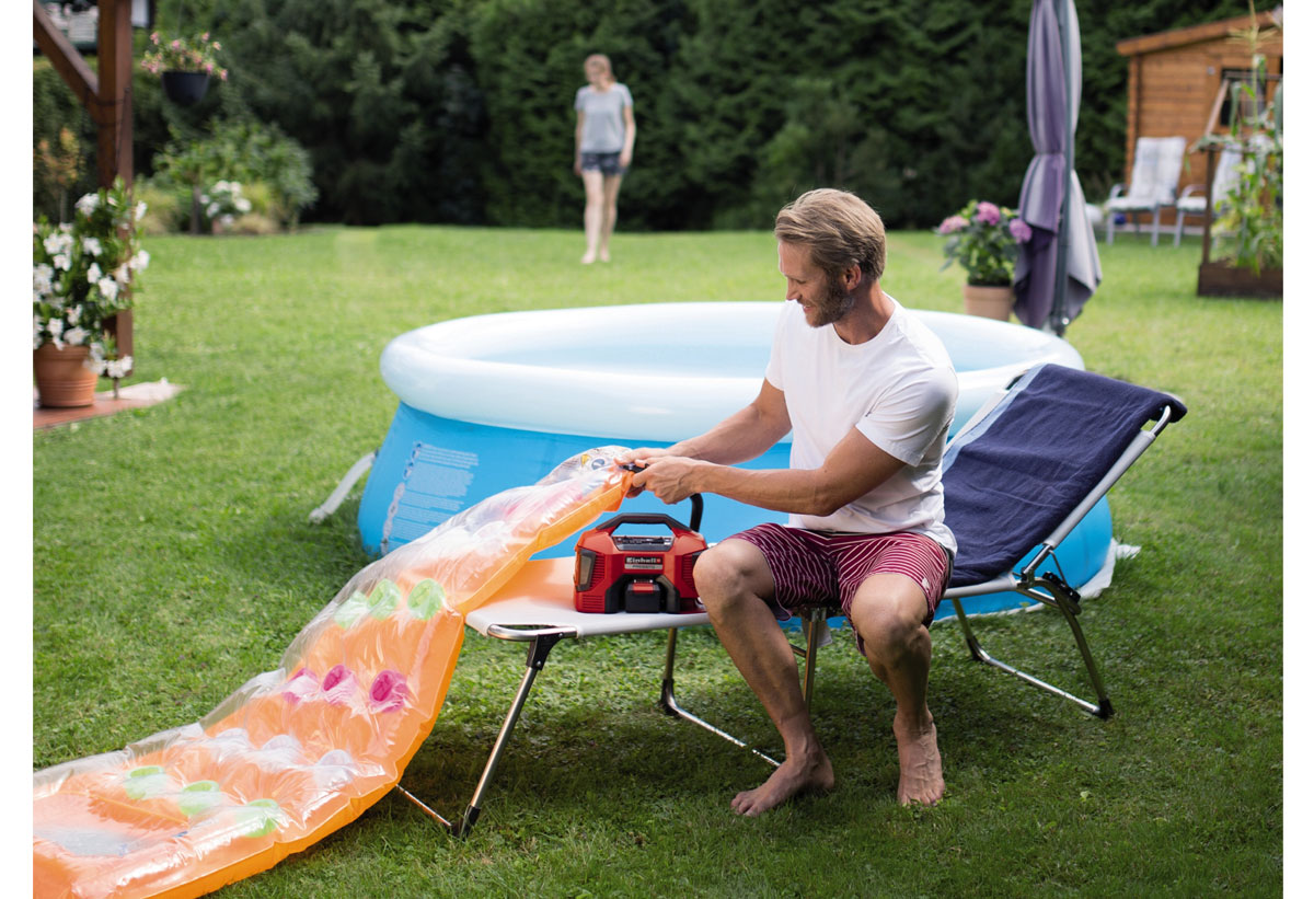 Απεικονίζεται άνδρας να χρησιμοποιεί τον αεροσυμπιεστή για το φούσκωμα στρώματος παραλίας.